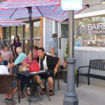 People sitting at cafe tables on a sidewalk in Marion.