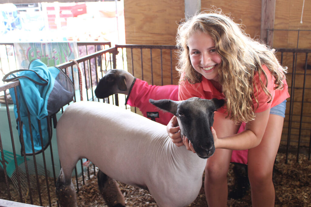 A girl posing for a photo with her sheep at the Marion County Fair.