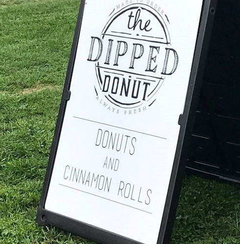 An outdoor sidewalk sign for The Dipped Donut.