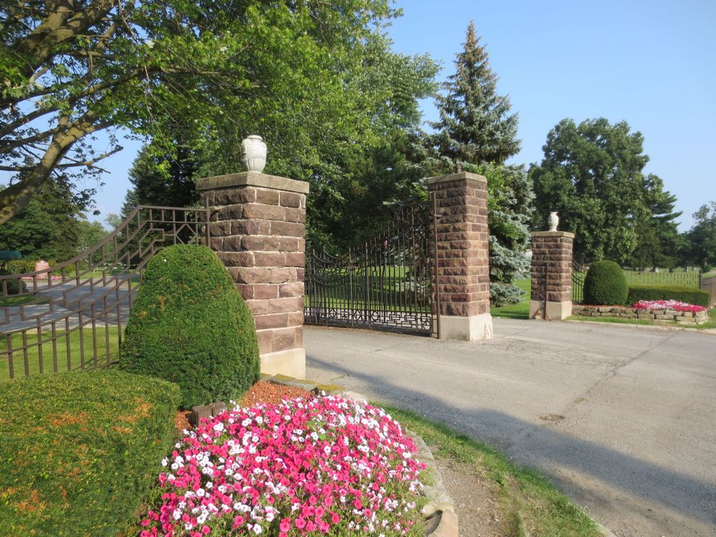 stone columns, gates, and flowers marking the entrance drive to the Marion Cemetery