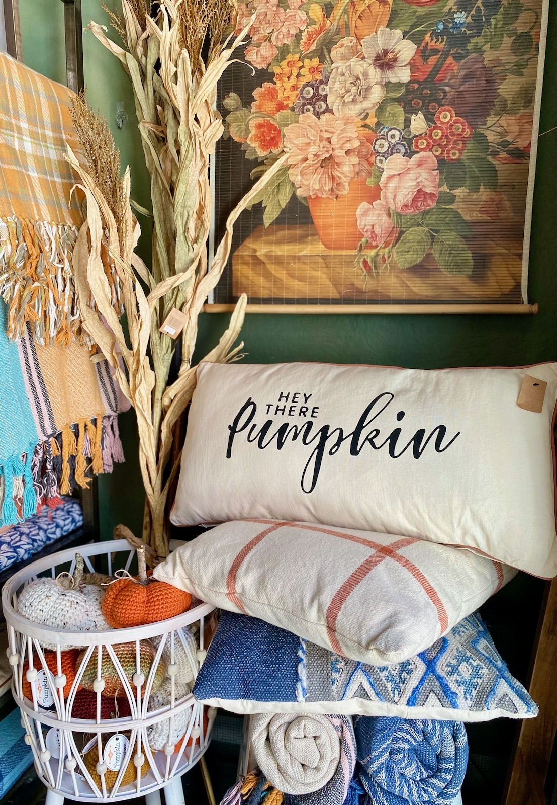 fall colored decor with floral art, embroidered pillows, blankets, and crocheted pumpkins