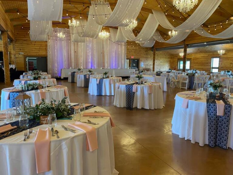 Rustic barn-like setting with round tables and fabric draped from the ceiling