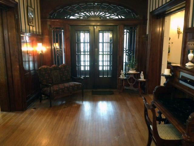 Entry way with doors and sidelights, wood floors, and antique furnishings