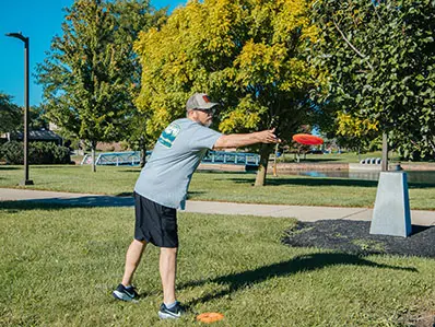 Man throwing a frisbee at a disc golf hole at OSU Marion