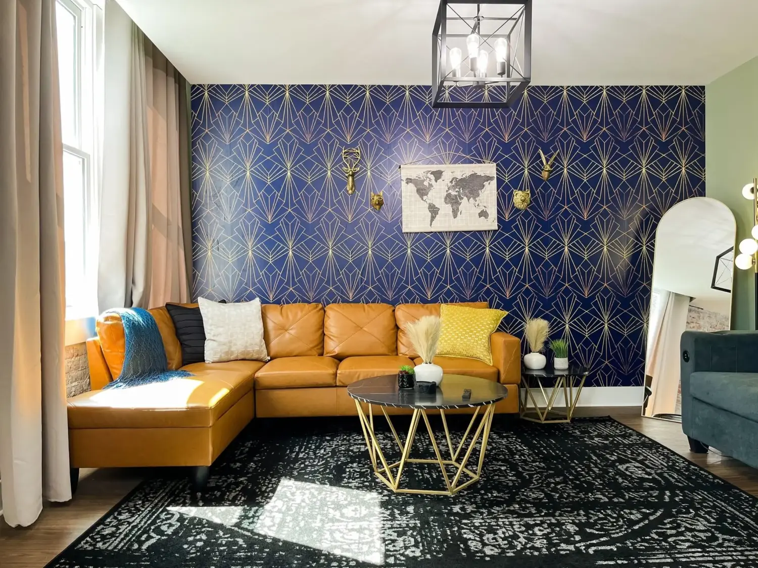 Living room of a Marion short-term rental with a navy and gold geometric accent wall and a tan leather sectional